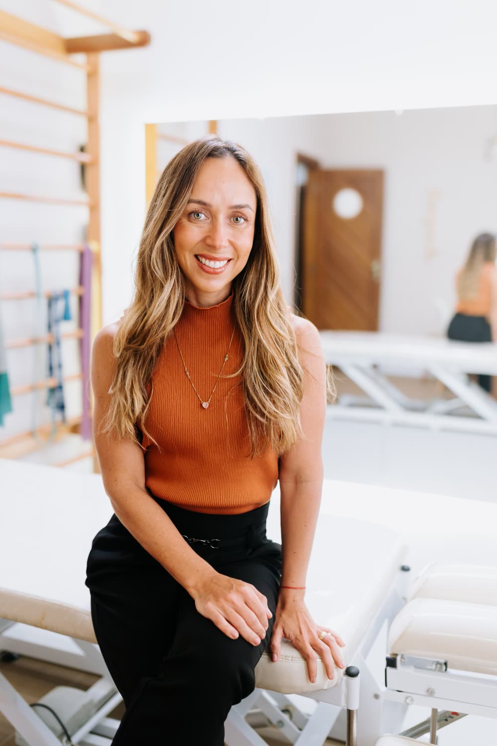 Priscila Soares, fisioterapeuta, sorrindo na sala de fisioterapia
