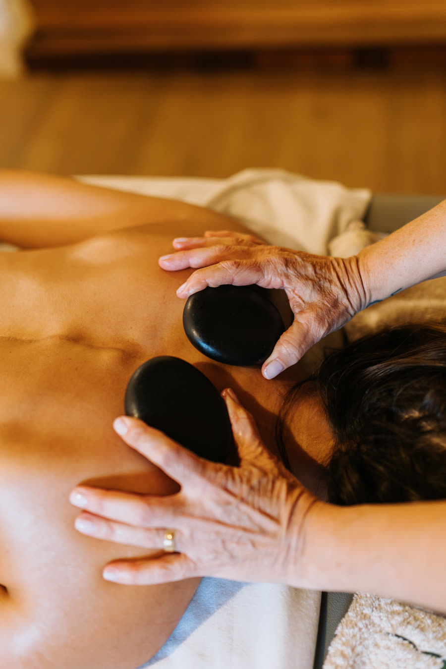 Terapeuta posicionando pedras quentes nas costas da cliente durante a massagem
